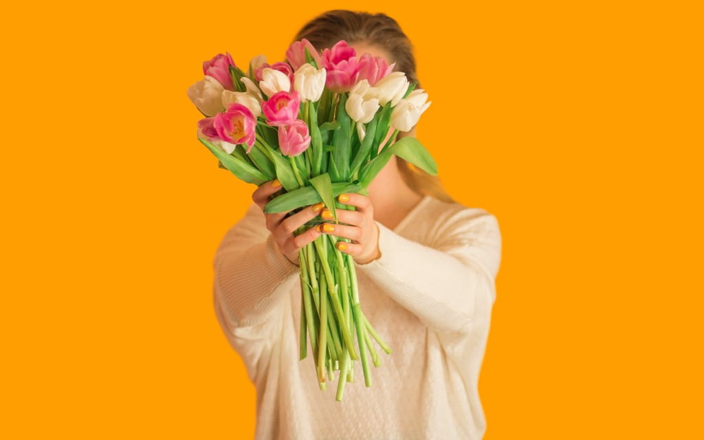 Frau hält einen Strauß Tulpen vor ihr Gesicht