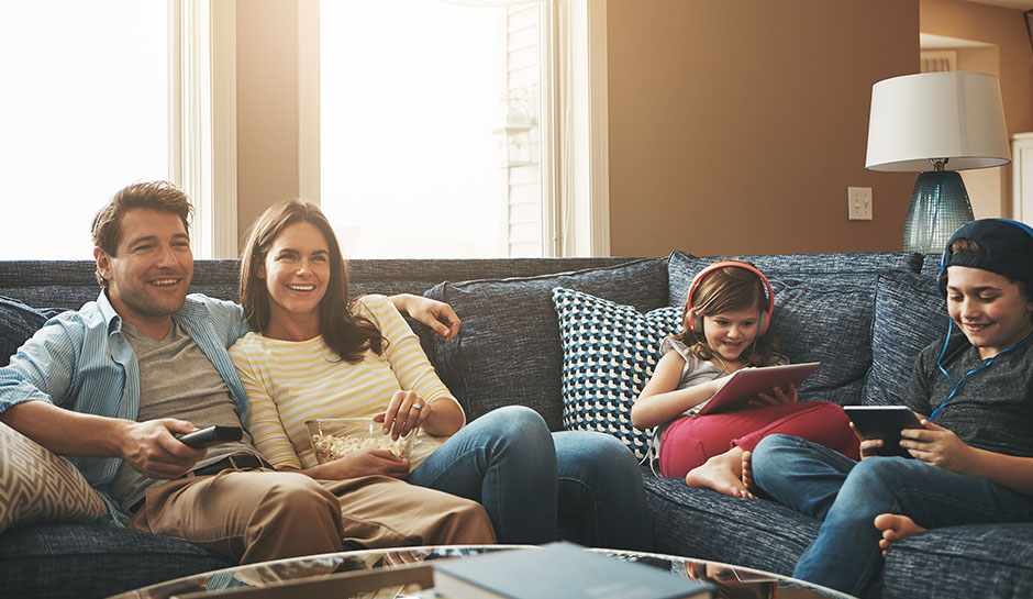 Familie schaut Fernsehen, während die Kinder ihre Tablets benutzen Familie schaut Fernsehen, während die Kinder ihre Tablets benutzen