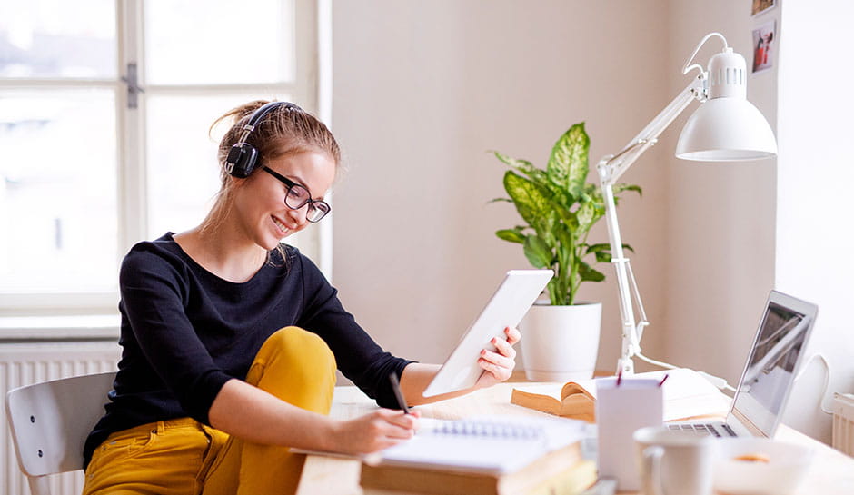 Studentin surft mit ihrem Tablet und hört dabei Musik Studentin surft mit ihrem Tablet und hört dabei Musik